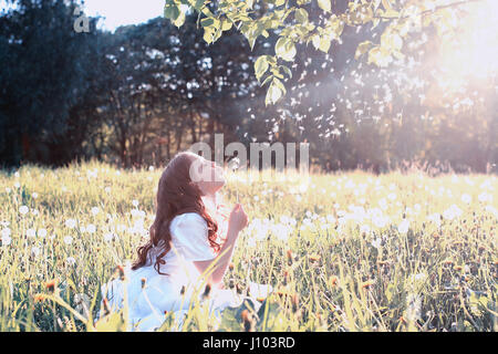 Teen girl blowing seeds à partir d'une fleur de pissenlit spring park Banque D'Images