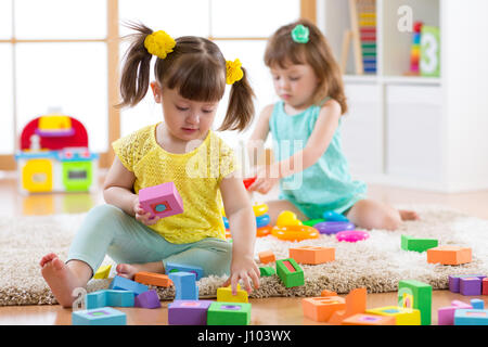 Les enfants jouent avec des jouets de bloc. Deux enfants la construction de tours à domicile ou garderie. Jouets éducatifs pour enfants d'âge préscolaire et de la maternelle. Banque D'Images