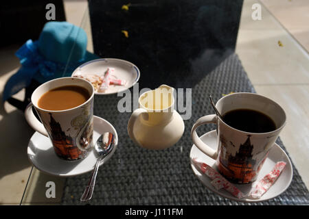 Deux tasse d'un café avec du lait et un sans avec un pot de crème entre debout sur une table en verre, photo de Chypre. Banque D'Images