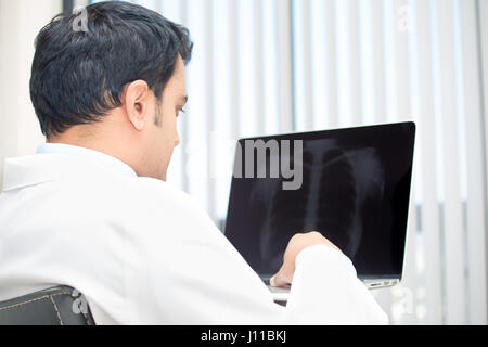 Closeup portrait of man intellectuelle avec le personnel des soins de santé, à la recherche à labcoat blanc chest x-ray image radiographique, sur ordinateur portable isolé c hôpital Banque D'Images