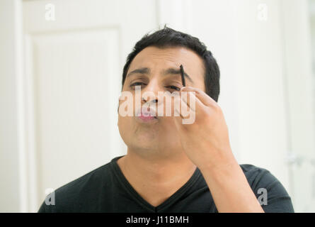 Closeup portrait, beau jeune homme égoïste en t-shirt noir à miroir en montrant des baisers et de canard, le peignage visage sourcils d'admirer son apparaître Banque D'Images