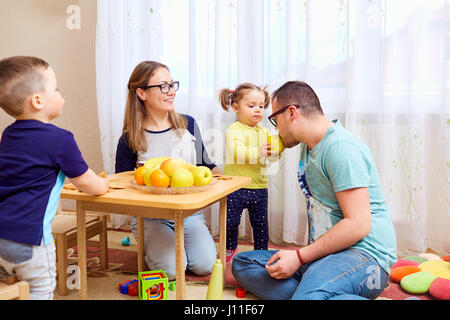 La fille nourrit son père avec une pomme dans la chambre Banque D'Images