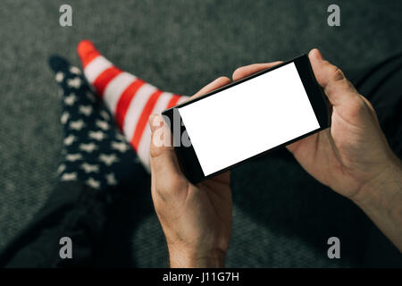 Des profils caucasian man wearing socks drapeau USA à l'aide de téléphone mobile tout en restant assis sur le sol Banque D'Images