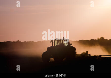 Silhouette de tracteur à travailler dans une ferme au crépuscule Banque D'Images