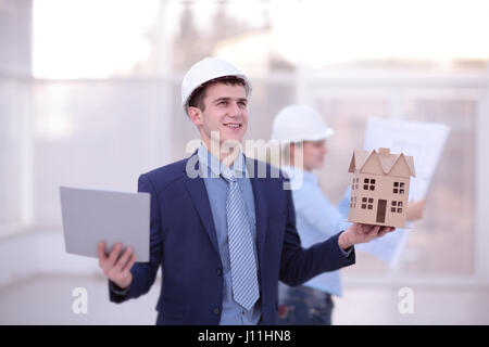 Deux collègues de travail et des données sur ordinateur portable, tablette avec sur le projet d'architecture at construction site at desk in office Banque D'Images