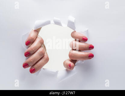 Woman's hands de déchirer le trou sur un papier. Banque D'Images