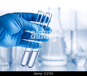 Béchers en laboratoire de l'analyste dans la main dans le gant en plastique. Banque D'Images