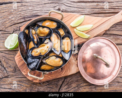 Les moules cuites en pan de cuivre sur la table en bois. Banque D'Images