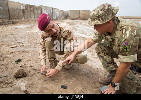 Un soldat des forces de sécurité irakiennes, se prépare à déclencher une interruption forcée de l'eau pour détruire une simulation d'explosion d'un engin explosif improvisé sous l'oeil attentif d'une armée britannique des explosifs et soldat. Formateurs britannique affecté au 2e Bataillon, duc de Lancaster Regiment et déployés à l'appui de la Force opérationnelle interarmées - opération conduite inhérentes, résoudre la lutte contre les IED au Camp Taji, l'Iraq, le 9 avril 2017. Cette formation fait partie de la Force opérationnelle interarmées combinée globale - Fonctionnement résoudre inhérent à renforcer les capacités des partenaires mission par la formation et l'amélioration des capa Banque D'Images