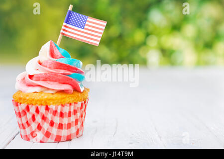 Rouge-blanc et bleu de cupcakes avec des drapeaux américains sur une table d'extérieur. Banque D'Images