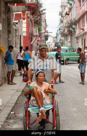 Une femme handicapée soit poussé dans un fauteuil roulant à La Havane, Cuba. Banque D'Images