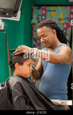 Un homme donnant à un jeune garçon d'une coupe à La Havane, Cuba. Banque D'Images