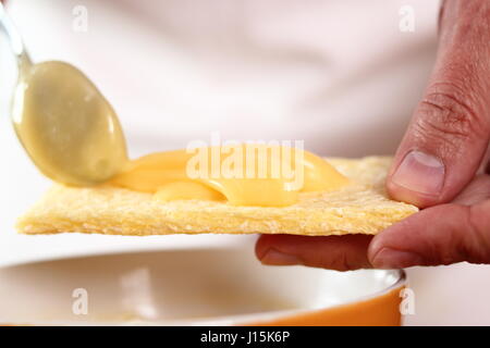 La diffusion de la mayonnaise sur le maïs croustillant. Faire de la mayonnaise avec une cuillère en bois. Banque D'Images