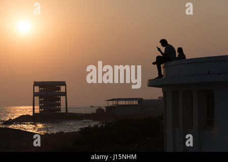 Deux hommes observant le coucher du soleil à Kanyakumari, India Banque D'Images