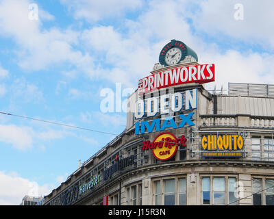 De l'extérieur de divertissement Printworks, dans le centre-ville de Manchester center, montrant tous les logos publicitaires colorés contre un ciel bleu. Banque D'Images