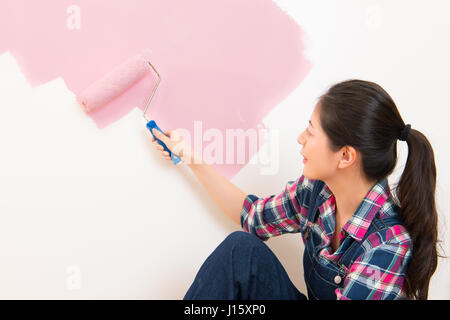 Certain young woman portrait tandis que la peinture nouvel appartement à rénover avec peinture couleur rose fille chinoise asiatique. modèle multiculturel Banque D'Images