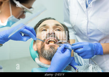 Travailler avec les médecins de soins dentaires du patient. Dentiste à l'aide de miroir concave. Banque D'Images