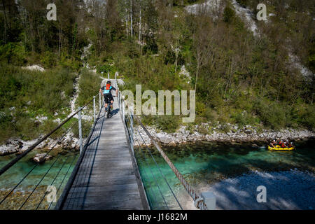 Une des promenades en vélo de montagne à travers un pont de bois sur la rivière Soca comme un groupe de rafting passe sous en Slovénie, l'Europe. Banque D'Images