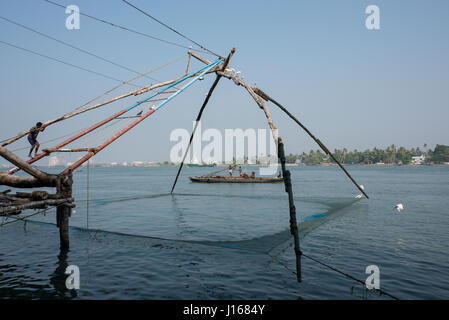 L'Inde, Etat du Kerala, port de la ville de Cochin. Filets de pêche chinois traditionnel (aka Cheena vala). Bateau de pêche dans la distance. Banque D'Images