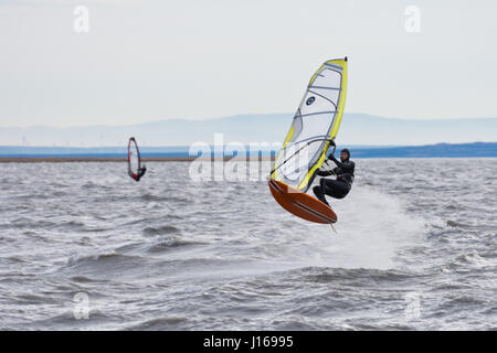 Planche sur le Neusiedlersee (Lac de Neusiedl) d'effectuer un saut dans le vent fort et les vagues. Temps froid, ciel nuageux Banque D'Images