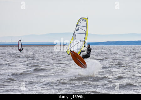 Planche sur le Neusiedlersee (Lac de Neusiedl) d'effectuer un saut dans le vent fort et les vagues. Temps froid, ciel nuageux Banque D'Images