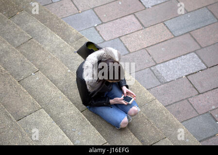 Jeune fille femme de s'asseoir et de fumer pendant l'utilisation de téléphone mobile Glasgow concert hall comme suit à la jonction de la rue Buchanan Sauchiehall Street Banque D'Images