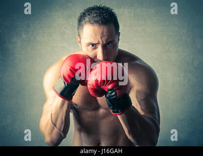 L'homme musclé avec des gants de boxe Banque D'Images