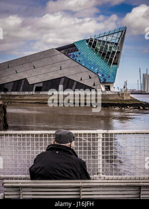 Old man wearing flat cap assis sur un banc à la recherche sur l'eau à la profondeur, une attraction touristique, Hull, Royaume-Uni. Banque D'Images