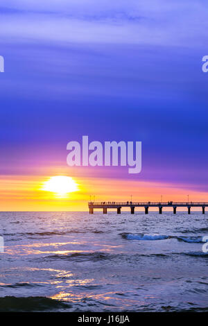 Jetée de piétons s'étend dans la mer. Au coucher du soleil dans la mer Baltique resort Palanga, Lituanie. Rayons de soleil à travers les nuages cirrus faible. Les raz de marée Banque D'Images