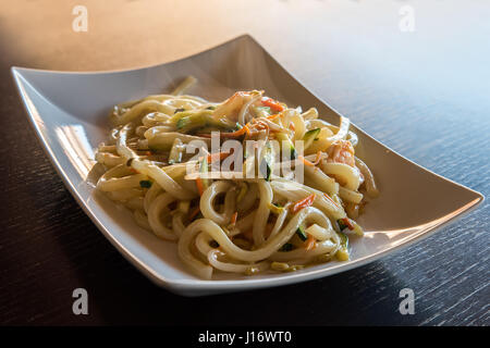 De délicieux aliments japonais yaki Udon, nouilles aux fruits de mer shrips,et les légumes,plaque blanche sur fond en bois. Banque D'Images