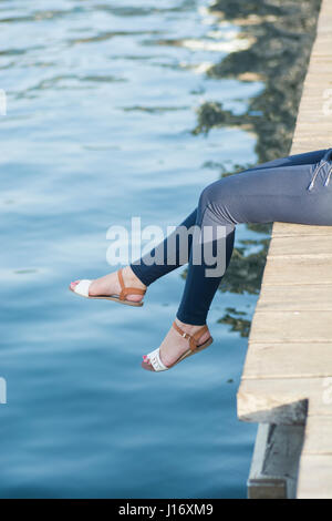 Close up of a woman's legs assis sur le quai par la mer Banque D'Images