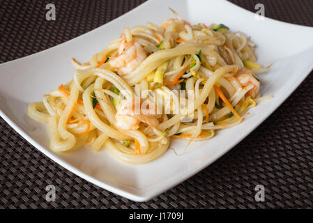 De délicieux aliments japonais yaki Udon, nouilles aux fruits de mer shrips,et les légumes,plaque blanche sur fond sombre. Banque D'Images