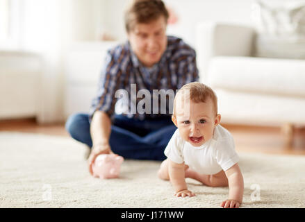 Heureux père avec bébé et tirelire à la maison Banque D'Images