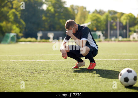 Triste joueur de foot avec ballon sur terrain de football Banque D'Images