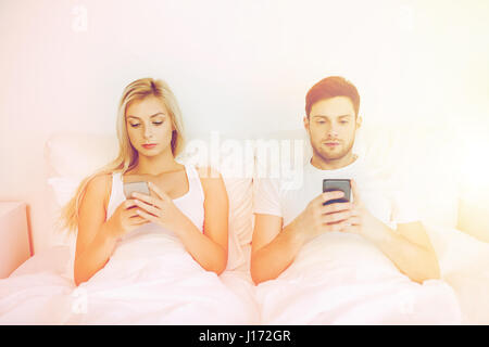 Les smartphones avec couple in bed Banque D'Images