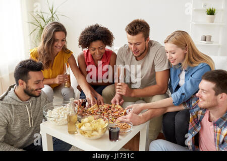 Happy friends avec boissons manger une pizza à la maison Banque D'Images