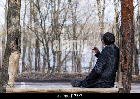 Fumeurs dans le manteau de l'homme ressemble à la Riverside de l'arrière Banque D'Images