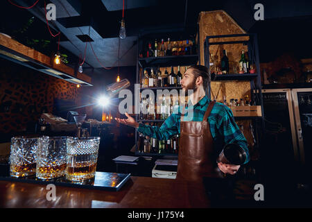 Le barman jongleur lance de un verre de cocktail au bar Banque D'Images