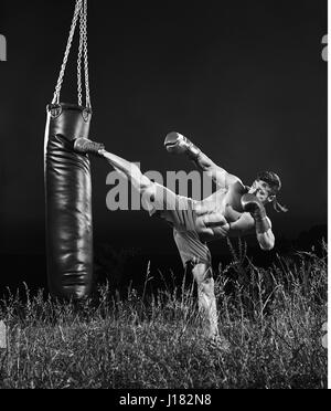 Plans d'un monochrome male boxer formation avec un sac de boxe ou Banque D'Images