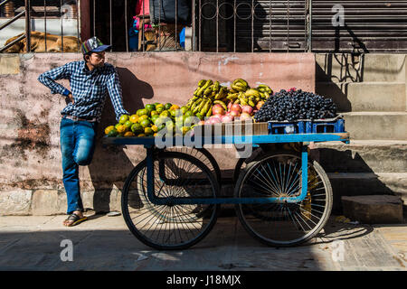 Un jeune homme vender vend des fruits de sa main panier sur les rues de Katmandou, près de la stupa de Boudhanath. Banque D'Images