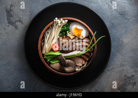 Nouilles Ramen avec du canard, oeuf, champignons shiitake et enoki bouillon avec sur fond sombre Banque D'Images
