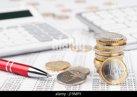 Finances comptabilité de l'entreprise stock fond avec pile de pièces en euros stylo rouge calculatrice et clavier sur fiche Banque D'Images