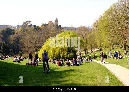 Les personnes bénéficiant du soleil du printemps dans le parc des Buttes-Chaumont, Paris, France Banque D'Images