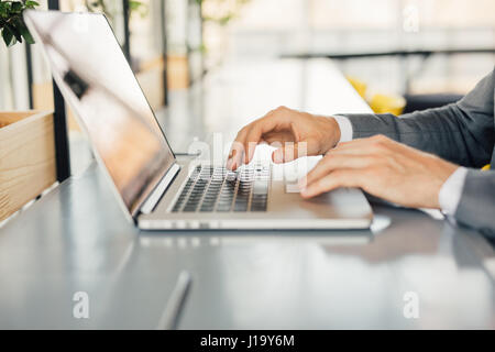 Businessman working on Photo bureau loft moderne. Homme assis et de tables en bois à l'aide de l'ordinateur portable contemporain, sms message clavier. À l'horizontal, film, f Banque D'Images