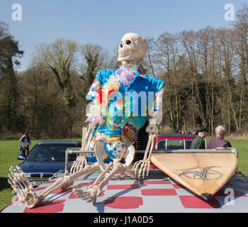 Squelette humain modèle sur toit de voiture habillé en chemise hawaïenne et avec une planche de surf Banque D'Images