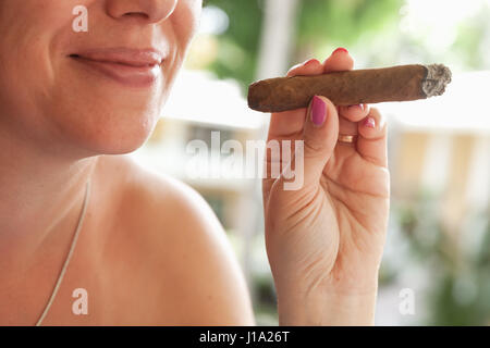 Young smiling woman européenne fume le cigare à la main, photo gros plan avec focus sélectif. République Dominicaine Banque D'Images