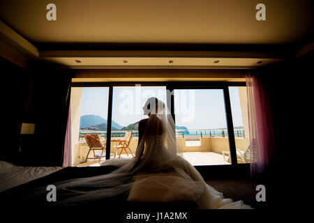 Silhouette d'une jeune mariée dans une robe de mariage sur une fenêtre dans un hôtel Banque D'Images