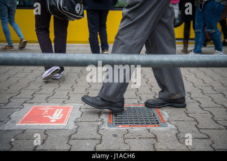 Stuttgart, Allemagne. Apr 19, 2017. Un homme marche sur un nouveau design cendrier intégré dans le sol à un arrêt de tram à Stuttgart, Allemagne, 19 avril 2017. Les fumeurs dans la ville sera en mesure de simplement laisser tomber son mégot sur le sol à l'avenir si la conception s'avère être un succès. L'opérateur de tramway Stuttgarter Strassenbahn (SSB) est actuellement à l'essai la conception à un arrêt dans le quartier de Vaihingen. Photo : Lino Mirgeler/dpa/Alamy Live News Banque D'Images
