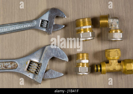 Différents outils sur un fond de bois. Clé ajustable et pièces pour la plomberie Banque D'Images