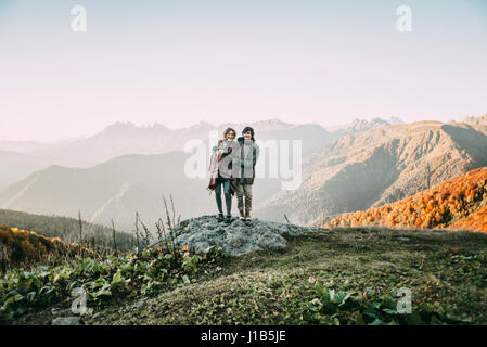 Caucasian couple standing on mountain rocher surplombant valley Banque D'Images